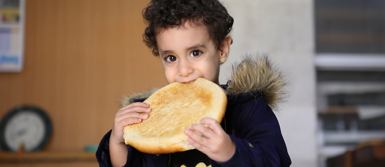 Primo piano di un bimbo di Betlemme che mangia del pane